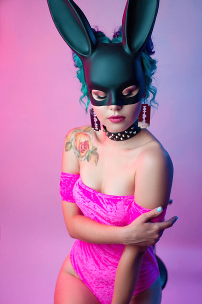 a woman in a bright pink bodysuit and a rabbit mask poses against a bright background - Foto, immagini