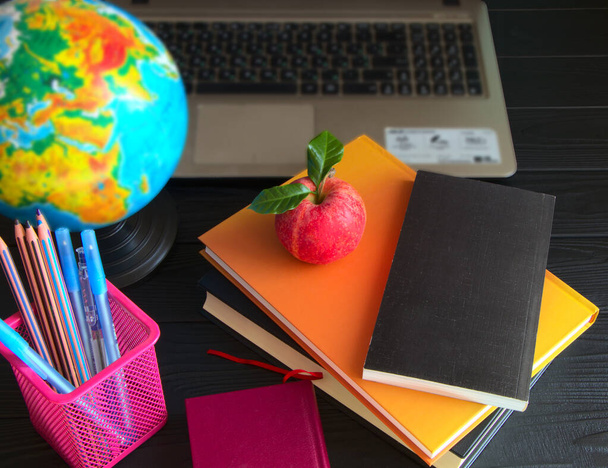 Scrivania per studenti con cancelleria e libri. Stack di libri e globo sulla scrivania. Laptop per l'apprendimento a distanza. - Foto, immagini