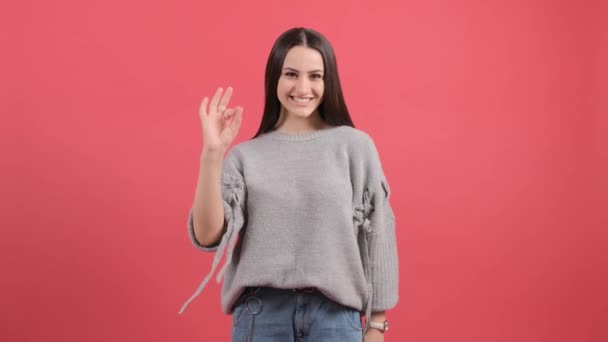 Boldog nő mutatja rendben jel ujjak elszigetelt felett piros háttér. - Felvétel, videó