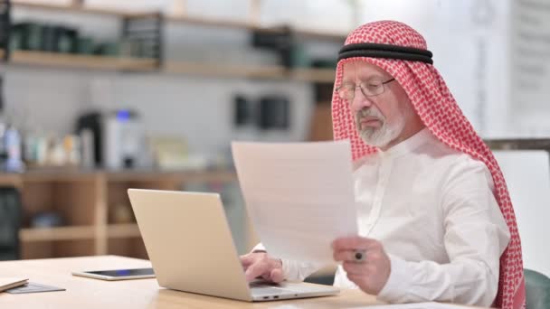 Oude Arabische zakenman werkt aan laptop en documenten  - Video