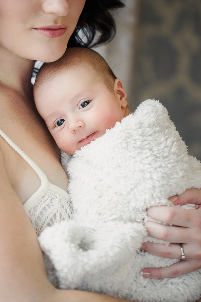 Portrait de heureuse jeune belle mère avec ses mains d'ion de bébé n intérieur de la maison
 - Photo, image
