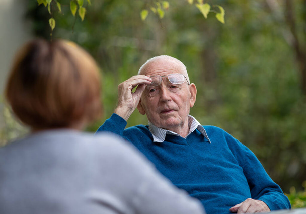 Portret van een oudere man die met zijn vrouw praat in het park. - Foto, afbeelding