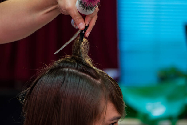 Beautiful teen girl at the hairdresser blow drying her hair after cutting it - Photo, Image