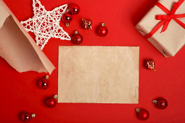 Mockup Vintage style blank für Weihnachtsmann Wunschliste für Weihnachten und Neujahr. Festliche Komposition mit Weihnachtskugeln auf rotem Hintergrund. Geschenkkarton und Kraft-Geschenkpapier mit Kopierraum. - Foto, Bild