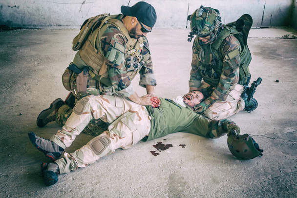 Soldado dando atención de emergencia a camarada herido - Foto, imagen