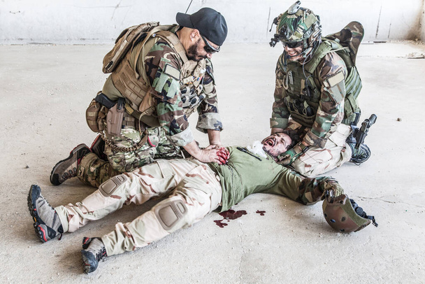 Солдат, оказывающий неотложную помощь раненому товарищу - Фото, изображение