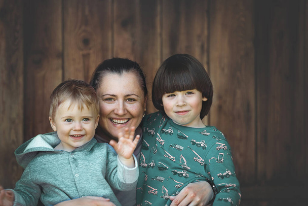 Moeder en twee zonen portret op houten achtergrond - Foto, afbeelding