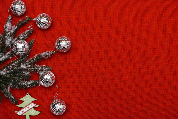 Modèle de Noël sur fond de tissu rouge avec place pour une inscription et boules de Noël et branches de sapin - Photo, image