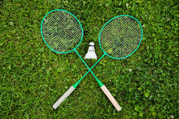 Crossed badminton rackets and shuttlecock on green grass, Badminton game, sport - Fotografie, Obrázek