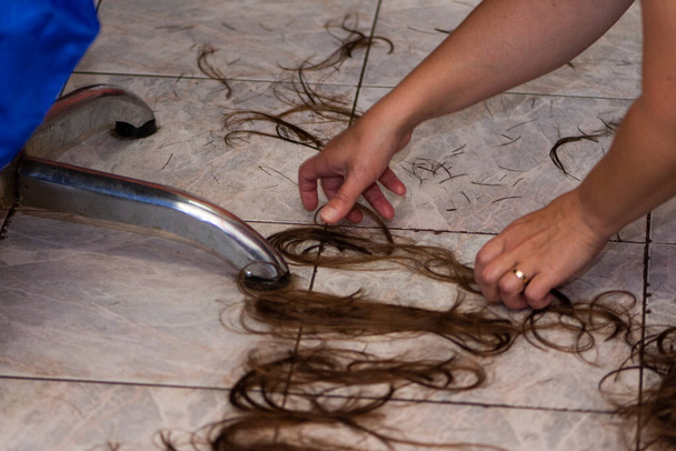Peluquería femenina escribiendo clientes nombre de su cabello en el suelo - Foto, imagen