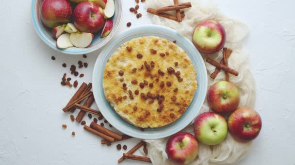 Домашний яблочный пирог на голубой керамической тарелке со свежими яблоками и коричными палочками - Кадры, видео