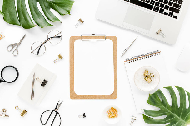 Home office workspace mockup with laptop, tropical leaves Monstera, clipboard, notebook and accessories on white background. Flat lay, top view - Photo, image