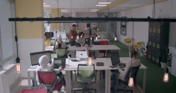 Młodzi ludzie o różnym pochodzeniu etnicznym pracujący w nowoczesnym biurze w dzień - Materiał filmowy, wideo