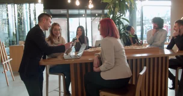 Giovani colleghi che discutono di un progetto in un bar durante la pausa pranzo - Filmati, video