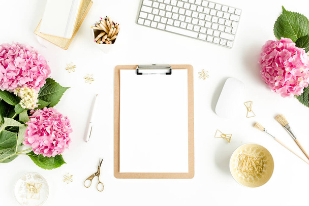 Stylized womens desk. Workspace with clipboard, computer, bouquet hydrangea, accessories on white background. Flat lay. Top view. - Foto, Bild
