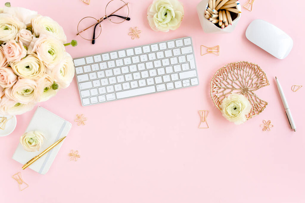 Stylized, pink womens home office desk. Workspace with computer, bouquet ranunculus and roses, clipboard on pink background. Flat lay. Top view. - Фото, зображення