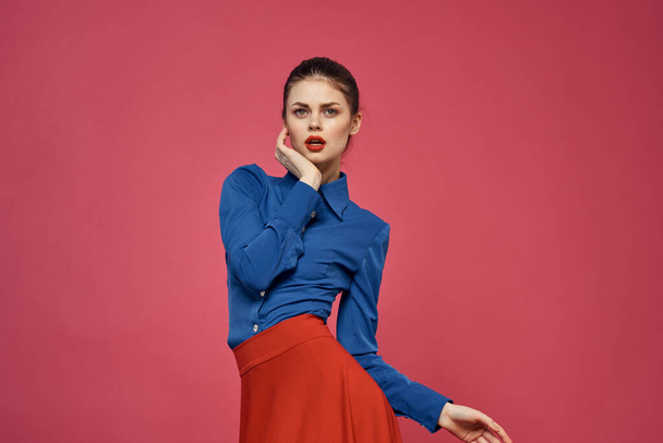 Mavi gömlekli ve pembe arkaplanlı kırmızı küplü bir kadın. - Fotoğraf, Görsel