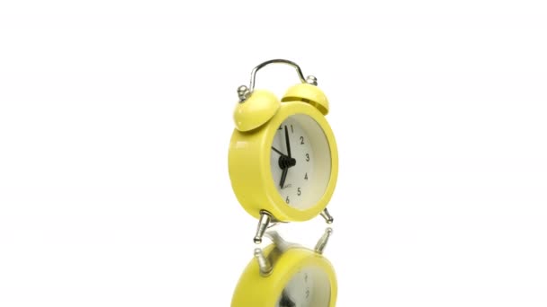 Small yellow vintage alarm clock rotating isolated on white background - Footage, Video
