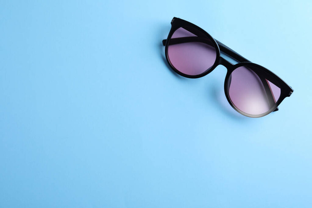 Stylish sunglasses on light blue background, top view. Space for text - Fotó, kép