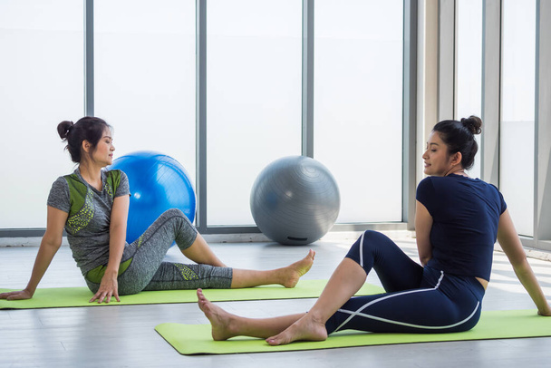 Twee aziatische vrouwen doen yoga samen in een sportschool. - Foto, afbeelding