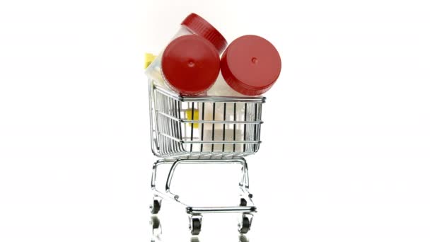 kleiner Einkaufswagen voller Tablettenflaschen 360 auf weißem Hintergrund rotierend - Filmmaterial, Video