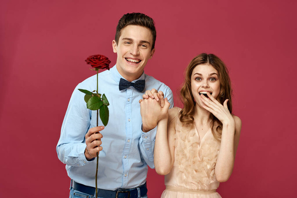 enamored man and woman with a red flower on a pink background hug each other Copy Space - Foto, imagen