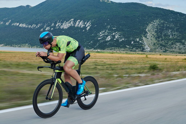 triathlon athlete riding professional racing bike at workout on curvy country road - Photo, image