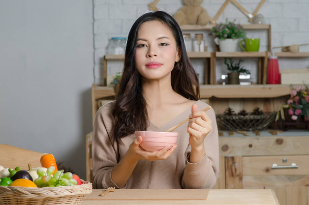 Happy young woman eating soup in kitchen - Photo, image