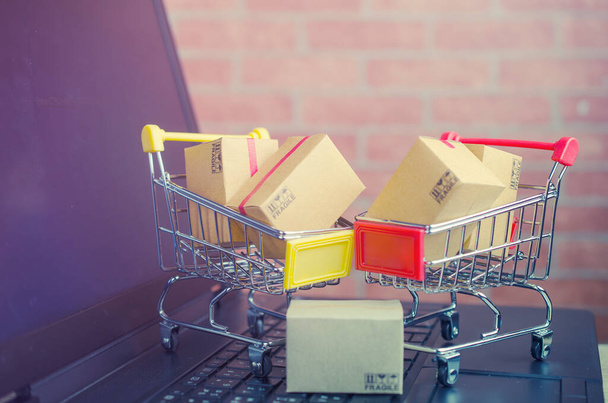 Papierboxen in einem Warenkorb auf einer Laptop-Tastatur, E-Commerce oder elektronischem Handel ist eine Transaktion zum Kauf oder Verkauf von Waren oder Dienstleistungen online über das Internet. - Foto, Bild