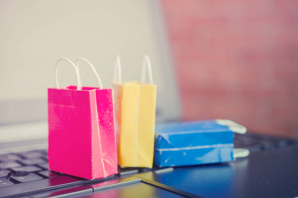 Colorful paper shopping bags on a laptop keyboard,e-commerce or electronic commerce is a transaction of buying or selling goods or services online over the internet. - 写真・画像