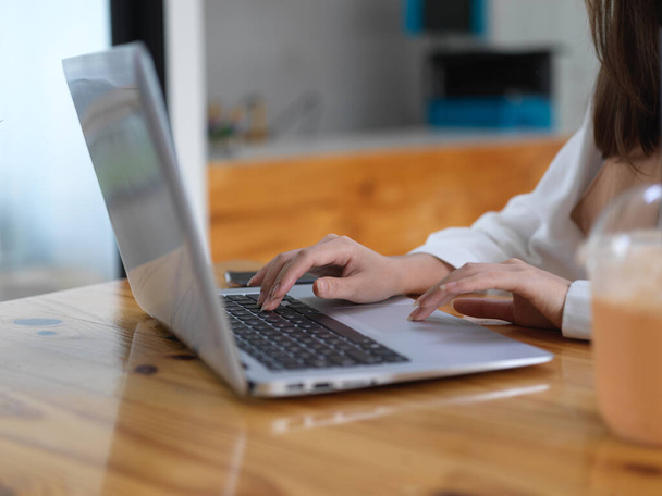 Πλευρική άποψη της γυναικείας δακτυλογράφησης μαθητή στο πληκτρολόγιο laptop, ενώ κάνει την εργασία στο καφέ  - Φωτογραφία, εικόνα