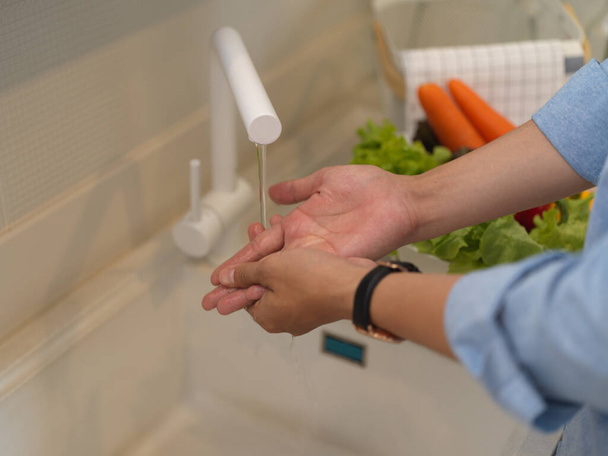 Cropped shot of female washing hands in kitchen sink while cooking in modern kitchen room  - Photo, image