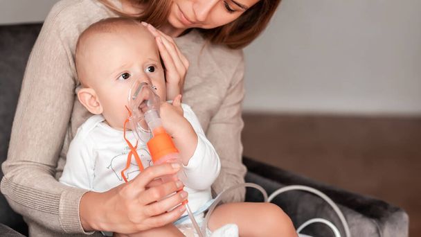 Mother using nebulizer for cute little baby at home. symptom of asthma or pneumonia cause by respiratory syntactical virus. Health care concept. - Photo, Image