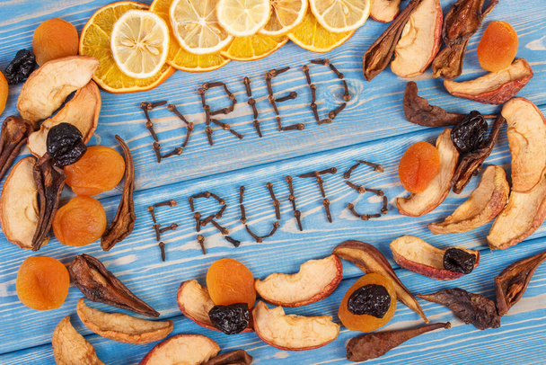 Inscription dried fruits and frame of ingredients for preparing beverage or compote of fruits on wooden boards, healthy nutrition - Foto, Imagem