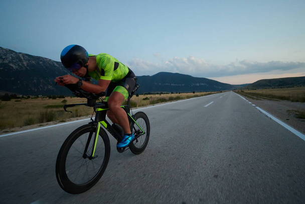 triathlon athlete riding professional racing bike at night workout on curvy country road w - Valokuva, kuva