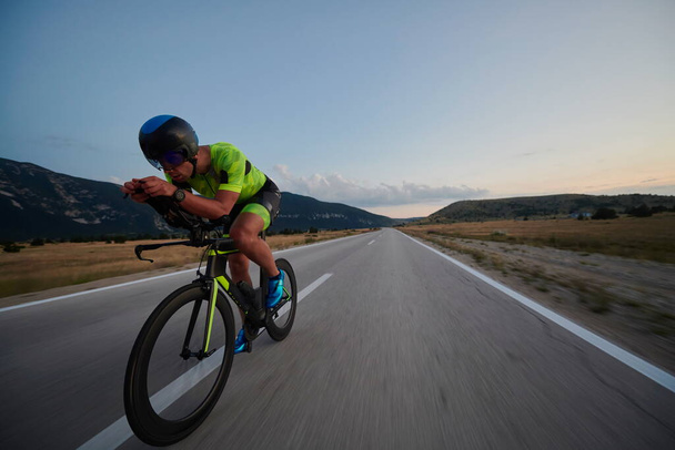 triathlon athlete riding professional racing bike at workout on curvy country road - Фото, зображення