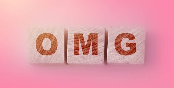 OMG escrito en cubos de madera sobre fondo rosa suave para la frase Oh Mine God. - Foto, imagen
