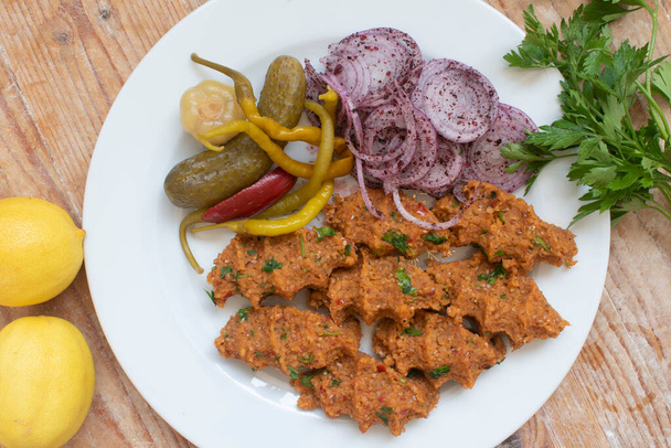 A comida turca serve-se com bulgur e lentilhas em uma chapa em um soalho de madeira. com salada de cebola, picles, salsa e limão. - Foto, Imagem