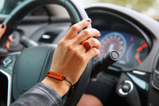 Shooting concept: girl s hands on the steering wheel of a car, a bracelet with the inscription dream on her hand. - Valokuva, kuva