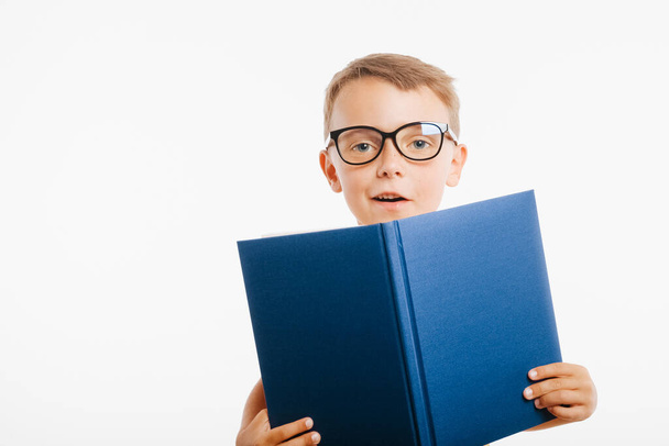 child reads a book against a bright wall - Zdjęcie, obraz