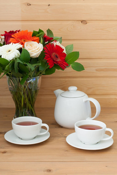 Teekanne, Tasse und ein schöner Frühlingsstrauß auf einem Holztisch. Tea Party. - Foto, Bild