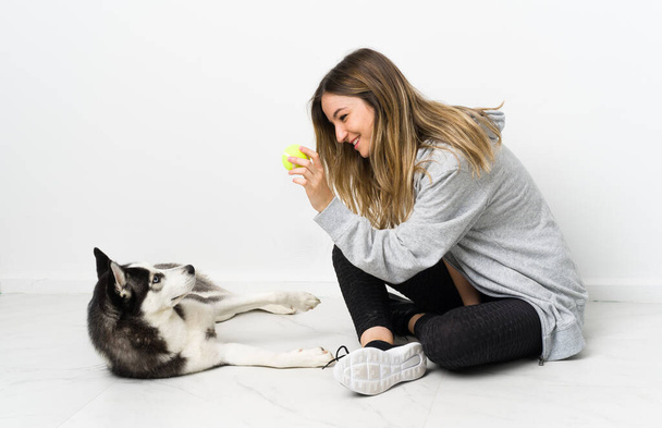 Young sport girl with her dog sitting on the floor - Photo, Image