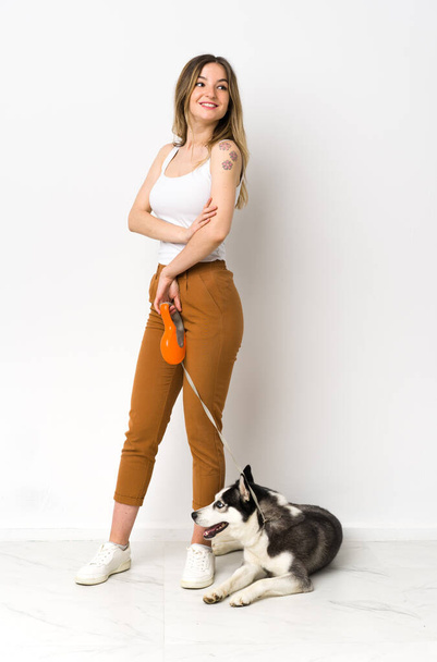 A full length young pretty woman with her dog with arms crossed and happy - Фото, изображение