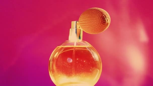 Golden fragrance bottle and shining light flares on pink background, glamorous perfume scent as holiday perfumery product for cosmetic and beauty brand - Footage, Video