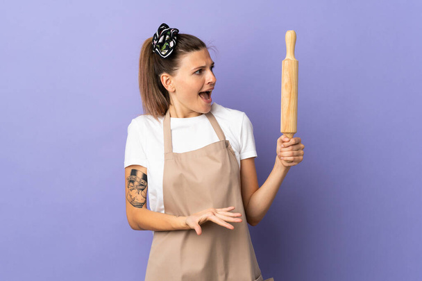 Kocher slowakische Frau isoliert auf lila Hintergrund mit überraschendem Gesichtsausdruck, während man Seite schaut - Foto, Bild