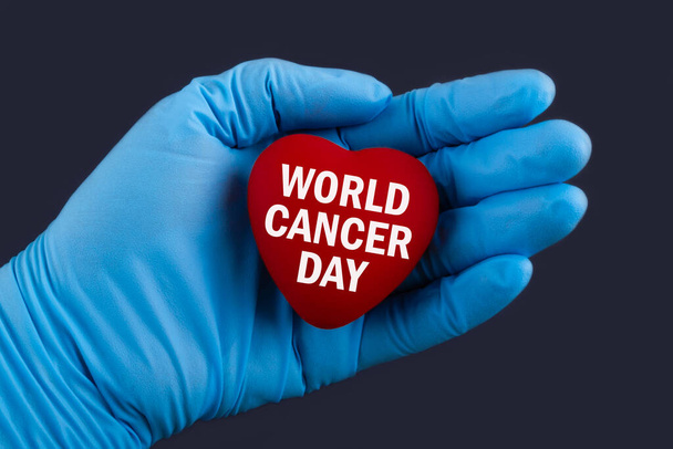 Doctor in blue gloves holds a heart with text world cancer day, concept. - Fotoğraf, Görsel