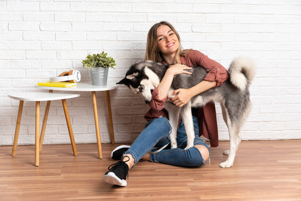 Junge hübsche Frau mit ihrem Husky-Hund auf dem Fußboden in Innenräumen - Foto, Bild