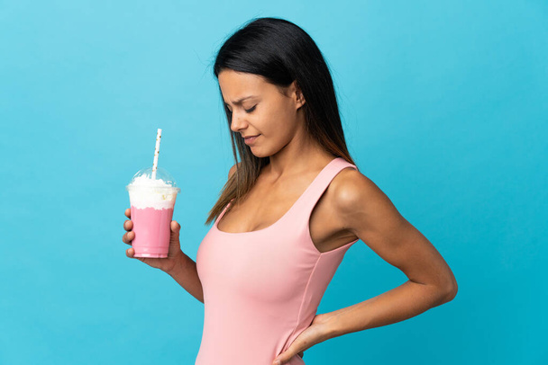 Jeune femme avec milkshake fraise souffrant de maux de dos pour avoir fait un effort - Photo, image