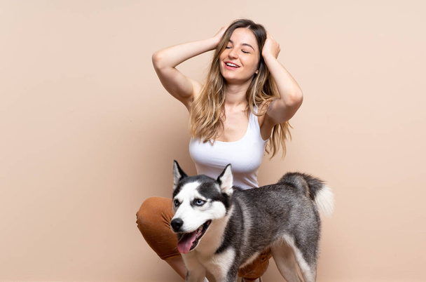 Young pretty woman with her husky dog sitting in the floor at indoors laughing - Photo, Image