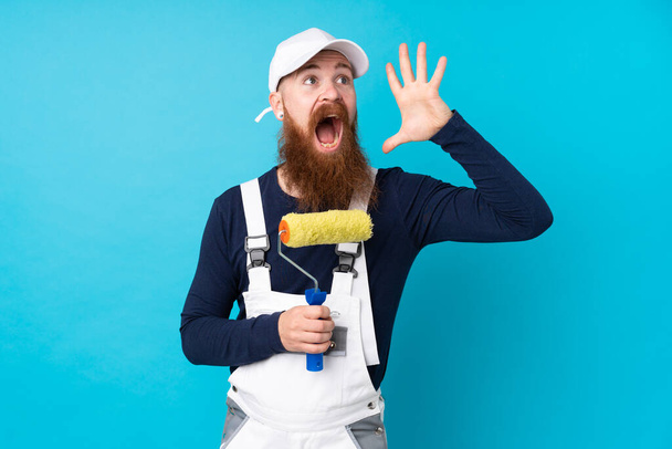 Художник с длинной бородой на изолированном синем фоне кричит с открытым ртом - Фото, изображение